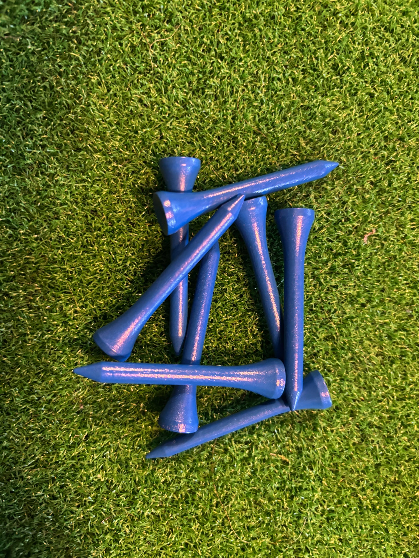 Blue golf tees on a green grass background