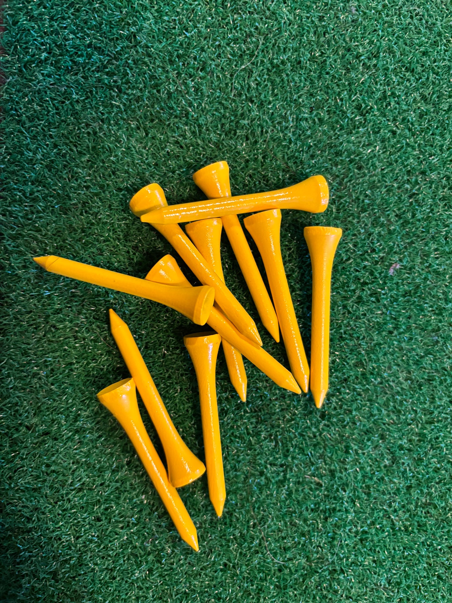 Yellow golf tees on a green grass background