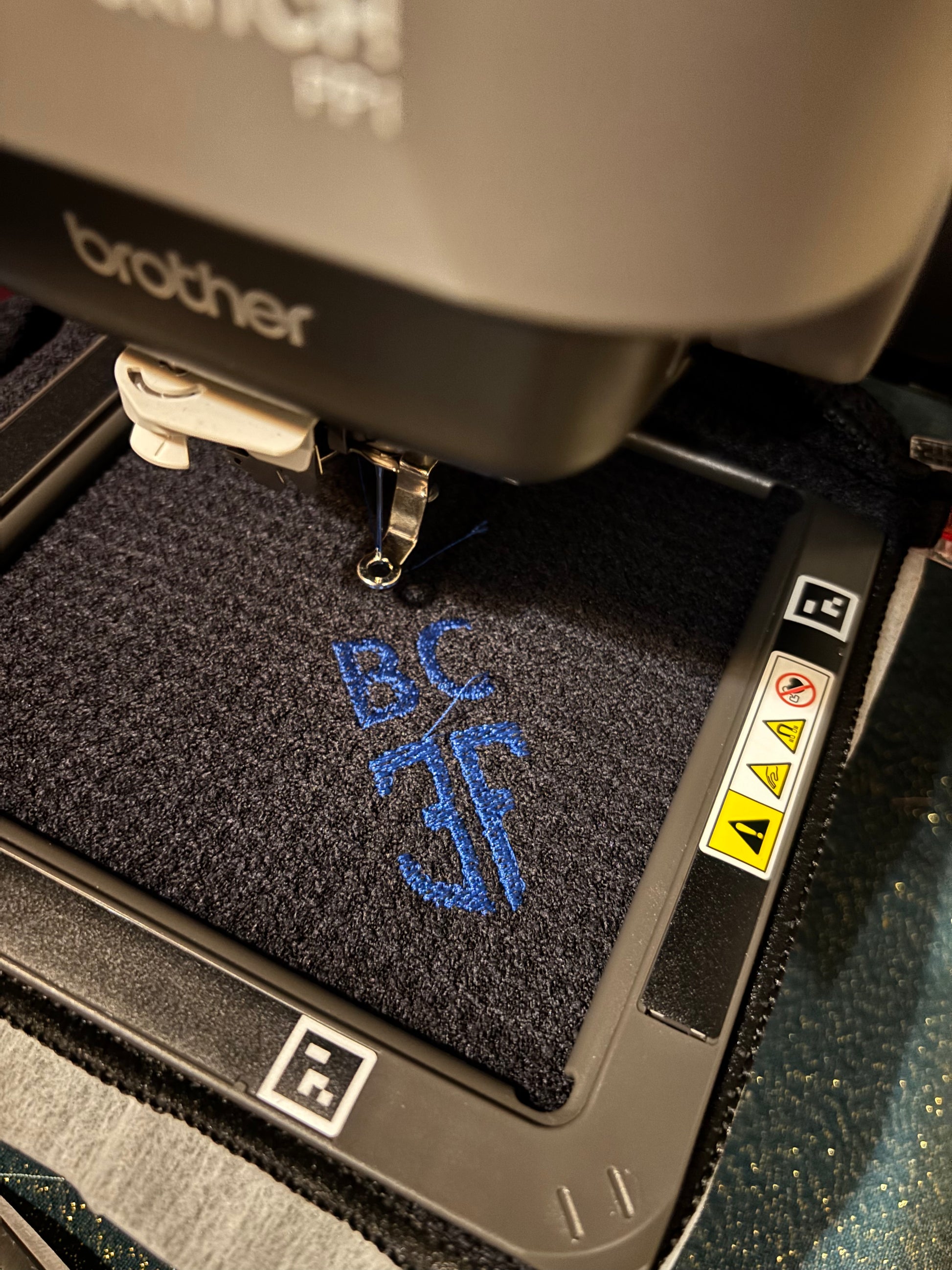 black waffle golf towel being embroidered with blue lettering 