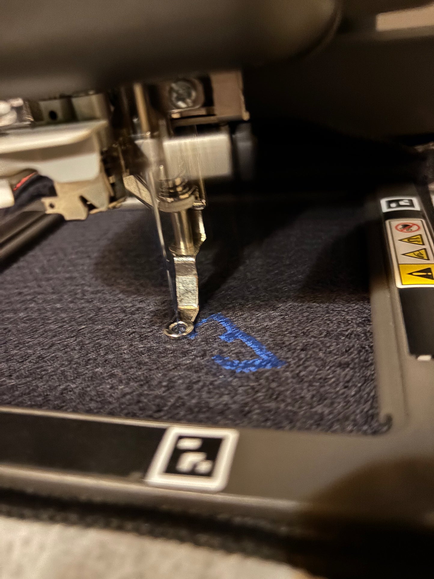 black waffle towel being embroidered with logo in blue