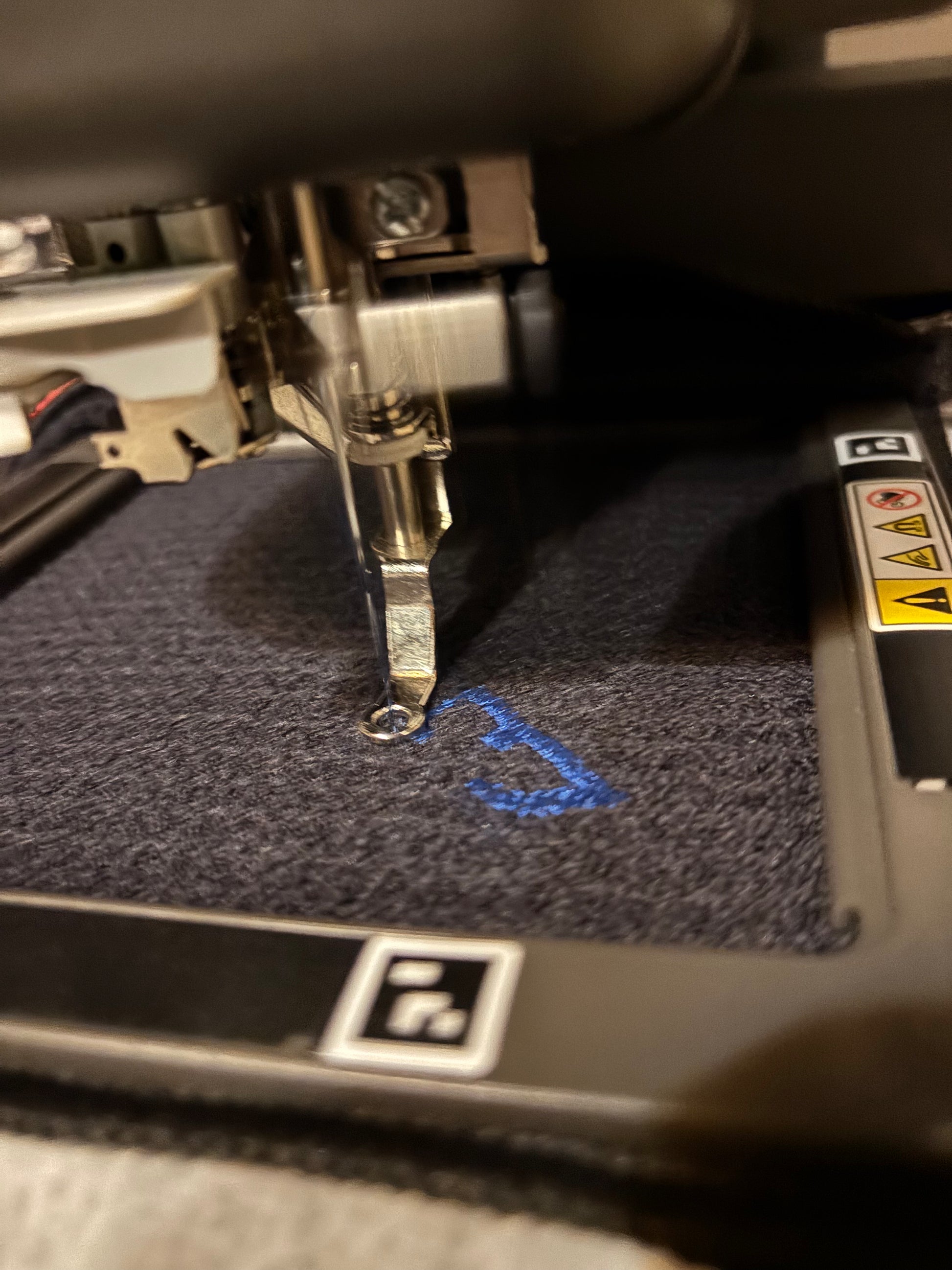 black waffle towel being embroidered with logo in blue