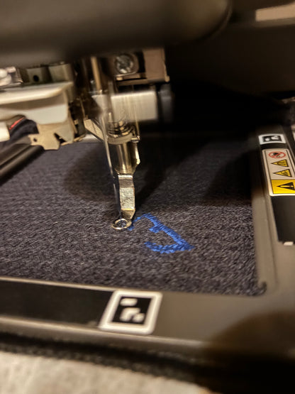 black waffle towel being embroidered with logo in blue
